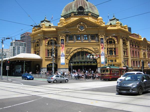 Flinders Street Station in Melbourne, yellow facade with dome, tram and traffic