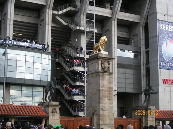 Golden lion statue on stone pillar, Twickenham stadium crowd on stairs