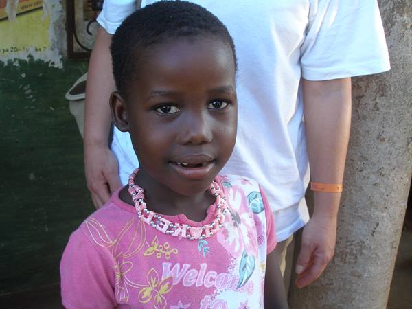 Smiling girl wearing a pink beaded necklace next to a person in white t-shirt