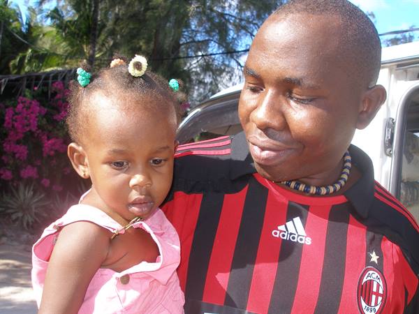 Man in AC Milan shirt smiles at a little girl among pink flowers