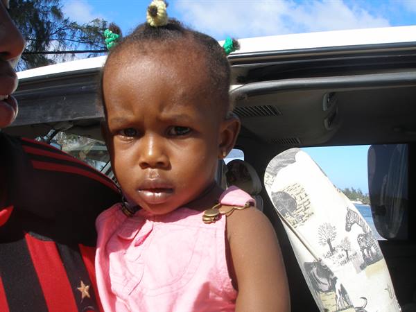 Little girl in pink dress held by a man inside a car