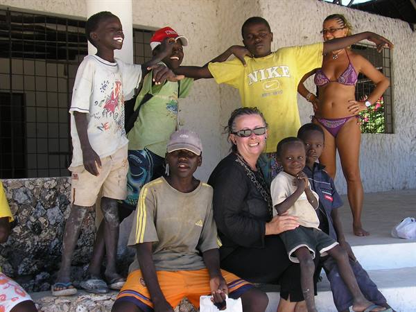 Woman and children smiling together on steps outside a white building