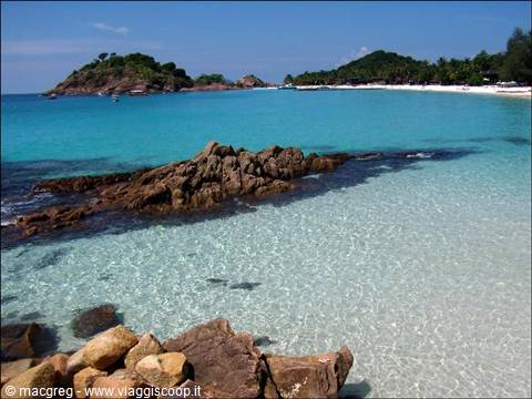Rocks on turquoise beach, green islets and boats, Pulau Redang