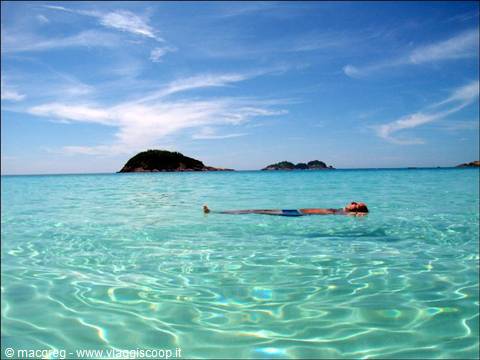 Woman floating on turquoise water in front of Spargi island, Maddalena