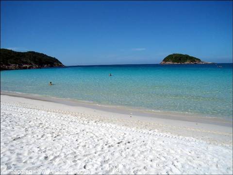 White sand beach, clear turquoise water, green islet, swimmers