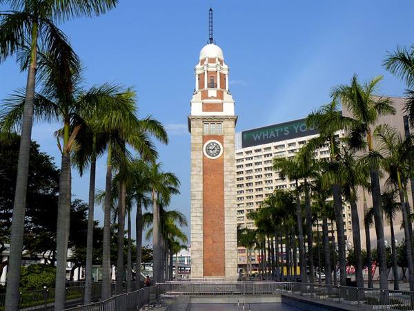 Red brick clock tower among palm trees in Tsim Sha Tsui, Hong Kong