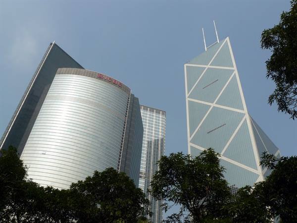 The Bank of China Tower in Hong Kong among glass skyscrapers and green trees