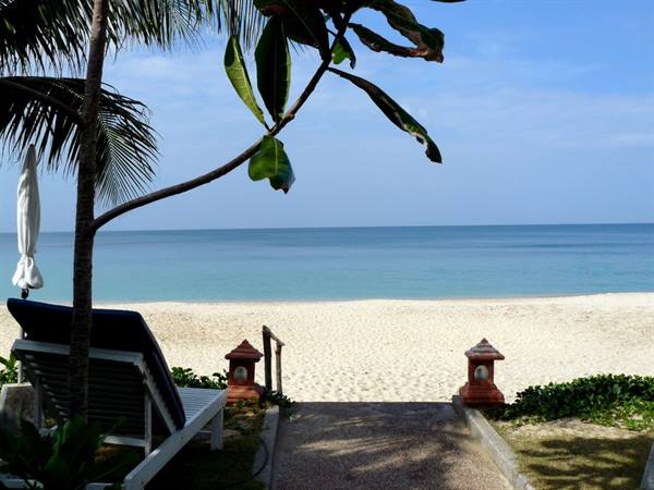 White sun lounger and red lantern on path leading to tropical beach