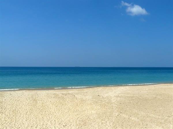 Golden sand and turquoise sea under blue sky with one cloud