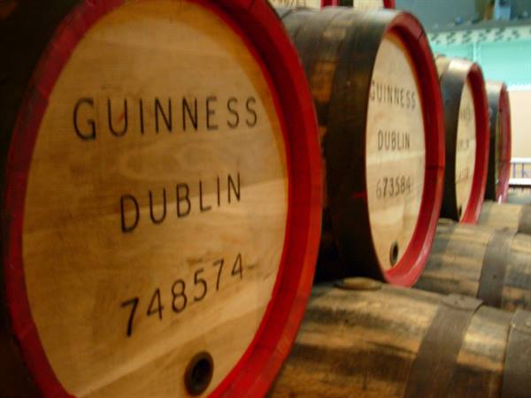 Guinness Dublin wooden barrels lined up with red hoops, warm light