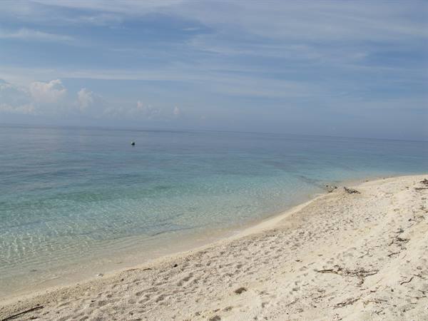 White sand beach with clear turquoise water and cloudy sky