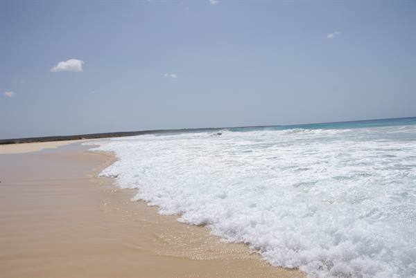 White waves breaking on golden sand of a deserted beach