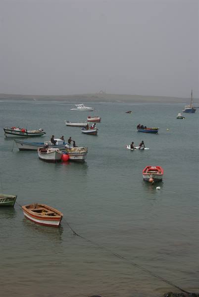Fishing boats moored in a hazy bay, men on small vessels
