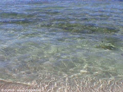 Crystal-clear water rippling over pale sand on a beach