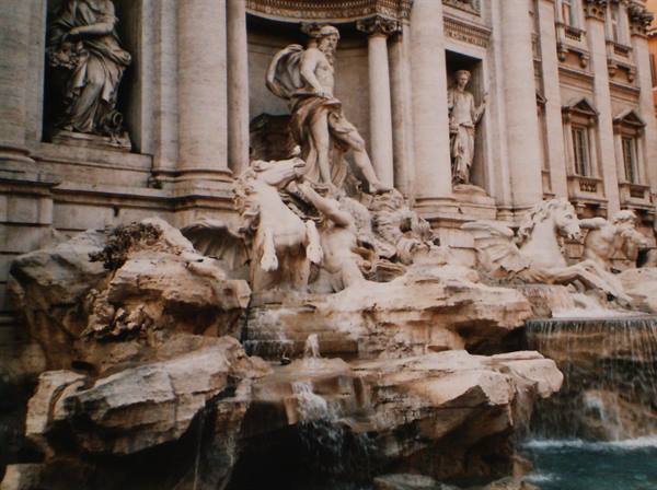 Marble statues and horses of the Trevi Fountain with flowing water