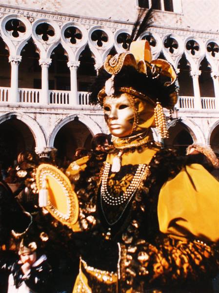 Masked reveller in golden yellow costume in front of Doge's Palace, Venice