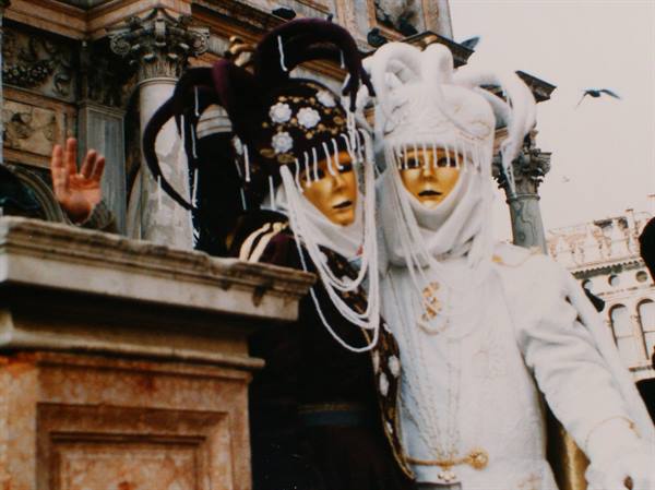 Golden carnival masks in costume in front of St Mark's Basilica