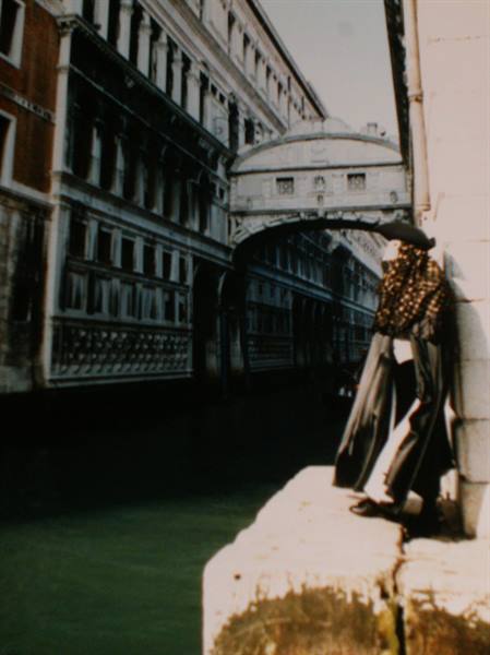 Venice, Bridge of Sighs: masked figure in cloak by the canal