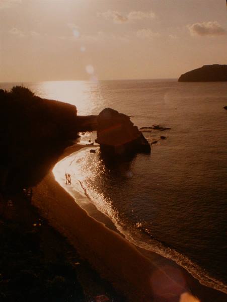 Sandy beach with offshore rock, golden low light on the water