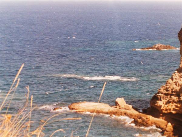 Rocky cliffs dropping into a deep blue sea with small islets