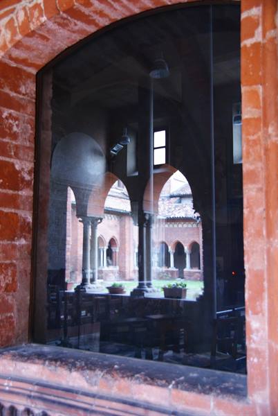 Romanesque brick cloister reflected in the glass of an arcade