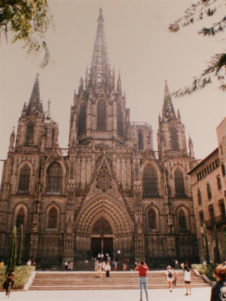 Gothic cathedral of Barcelona, stone facade with spires, tourists on the steps