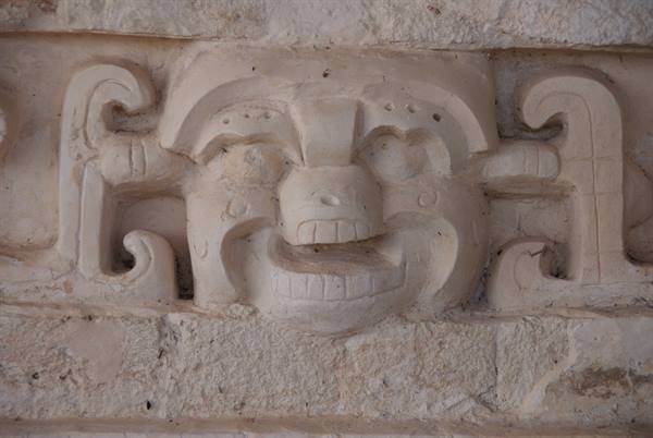 Carved limestone Maya mask with open jaws under natural light