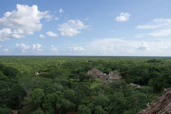 Ancient stone Maya ruins rising above the green jungle under a cloudy sky