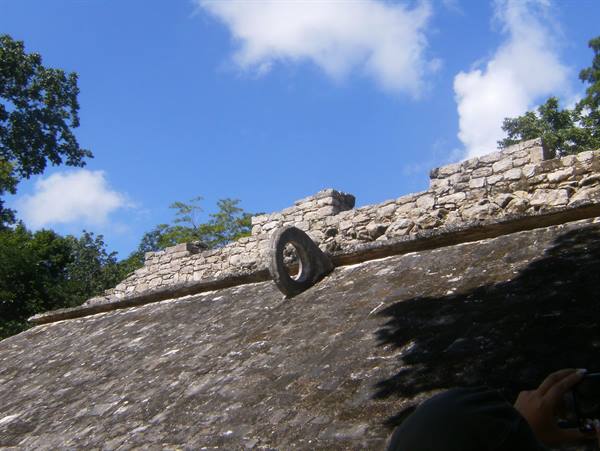 Stone ballgame ring atop a Mayan wall under blue sky