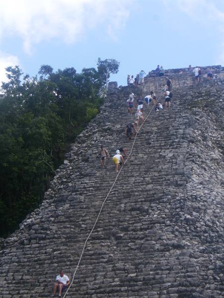 Tourists climb the steep stone pyramid at Cobá using a safety rope