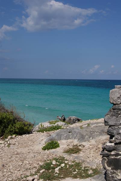 Ancient stone wall above rocky shore with turquoise water and blue sky