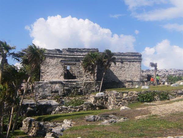 Mayan stone ruins at Tulum among palm trees and white clouds
