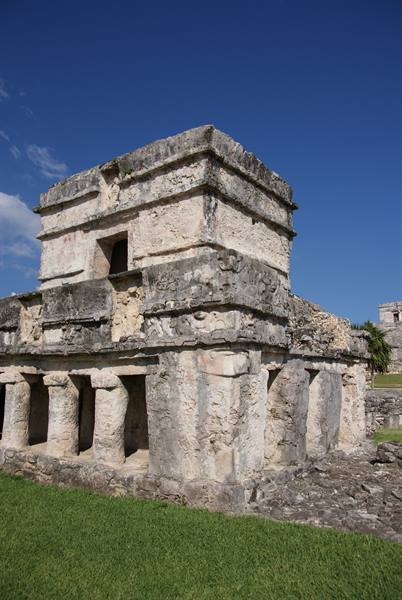 Mayan stone temple with columns, Tulum ruins under a blue sky