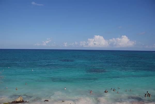 Swimmers in turquoise water under blue sky with white clouds