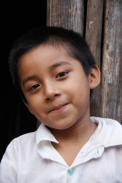 Portrait of a boy in a white shirt before a wooden door