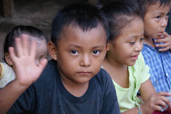 Children sitting together, one waving at the camera, soft natural light