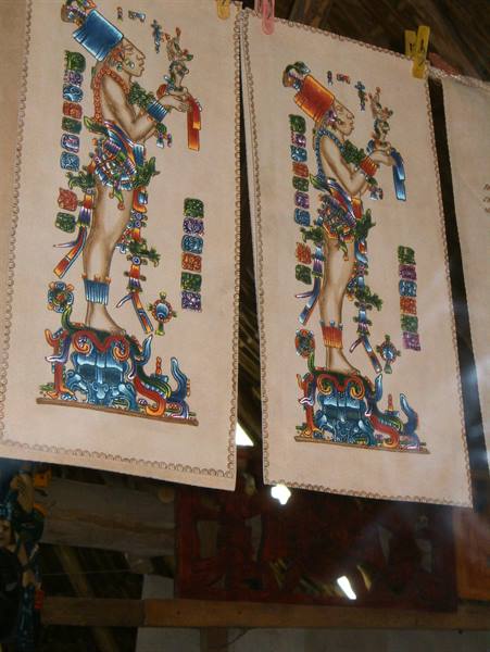 Colorful Maya paintings on amate paper hanging from wooden clothespins