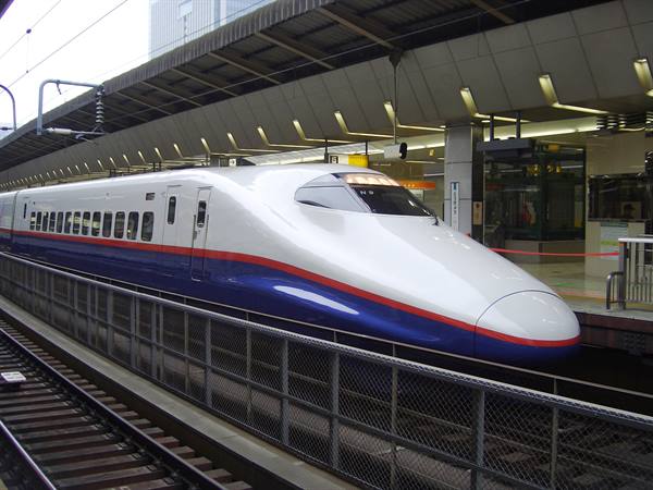 Shinkansen bullet train stopped at station, white nose with blue and red stripes