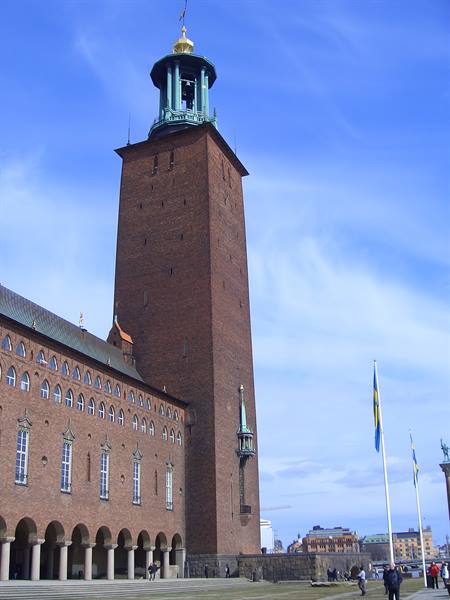 Red brick tower of Stockholm City Hall with Swedish flags waving