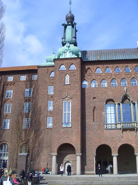 Stockholm City Hall, red brick tower with green copper spire, people below