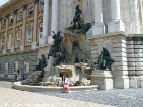Woman sitting in front of Matthias Fountain, Buda Castle, bronze statues