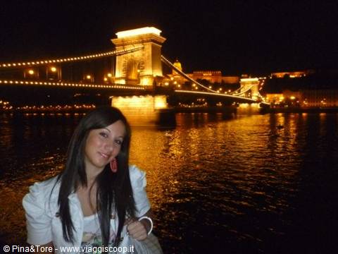 Smiling woman in front of the illuminated Chain Bridge at night, Budapest
