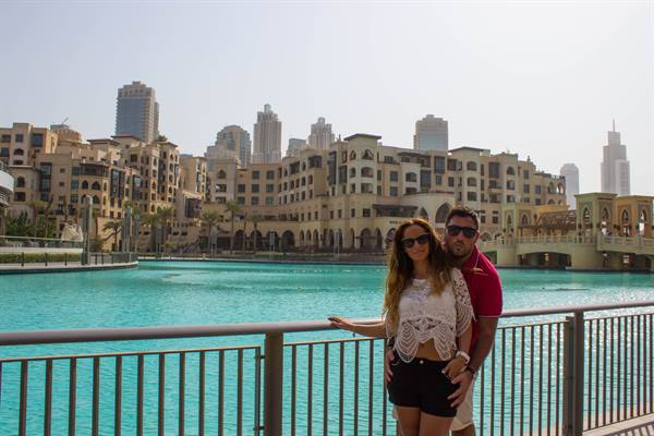 Couple leaning on the railing by the turquoise Burj Khalifa Lake, Dubai