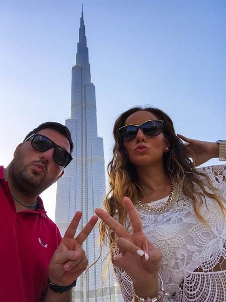 Two young people with sunglasses flashing peace signs at Burj Khalifa