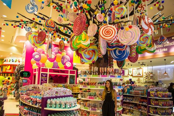 Woman in a candy store with colorful lollipops hanging from the ceiling