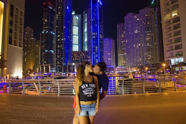 Couple kissing at night in Dubai Marina among blue-lit skyscrapers