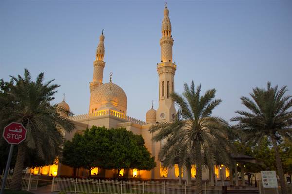 Jumeirah Mosque lit at dusk, minarets, domes and palm trees