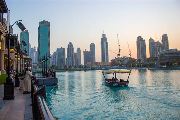 Traditional boat with passengers on the lagoon in front of Dubai skyscrapers
