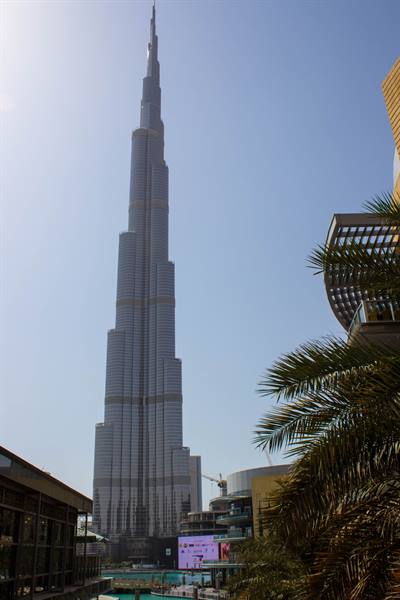 The Burj Khalifa towers over Dubai sky amid palm trees and buildings