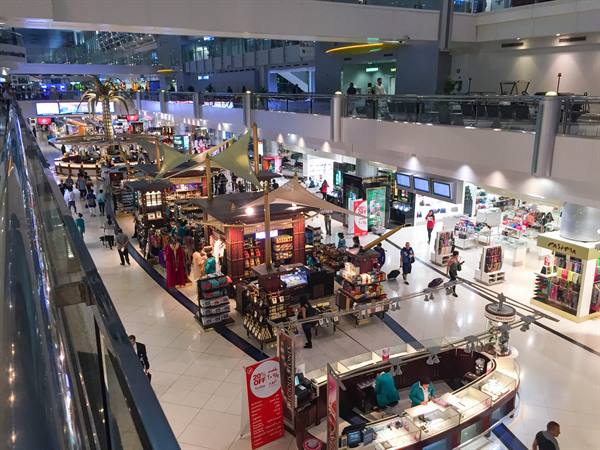 Dubai airport terminal with shops, kiosks and travelers under artificial lights